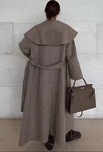 Back view of a long camel wool coat with a tie belt showing elegant drape and silhouette