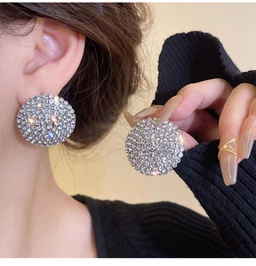 Macro detail of silver round earrings with sparkling pavé rhinestones on model side profile