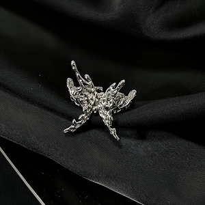 Detailed macro view of irregular silver butterfly ring with molten metal texture on silk