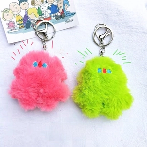 Macro detail of fluffy pink and green plush monster keychains with embroidered eyes