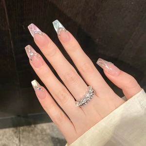 Dettaglio macro di unghie finte coffin con linee glitter argento e anello di diamanti