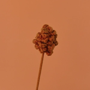 Handmade brown crochet Santa flower branch bouquet accessory on a warm peach background
