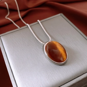 Detail of amber resin oval pendant showing glossy texture on silver box chain necklace