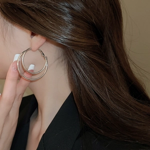 Detail of double-layer gold hoop earrings featuring textured inner and polished outer rings