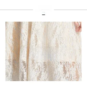 Detailed macro view of cream lace fabric featuring delicate white floral embroidery patterns