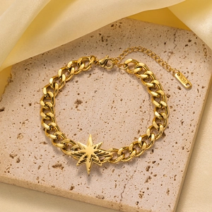 Detalle de pulsera de acero dorado con colgante de estrella de ocho puntas y cadena de eslabón