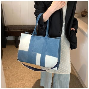 Detail view of the contrast denim patchwork and H-shaped strap design on a tote bag