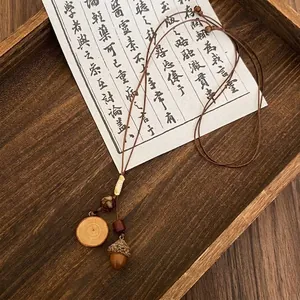 Detail view of retro forest necklace with acorn and wood slice pendants on leather cord