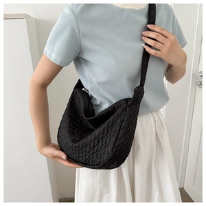 Detail showing the black bubble textured fabric and ruffled strap of the shoulder bag