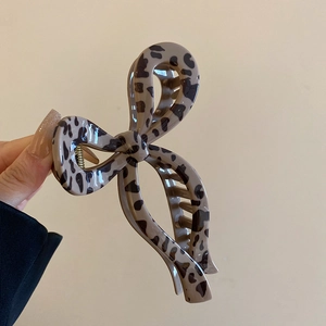 Detail of a large leopard print hair claw clip in a stylish bow shape and glossy finish