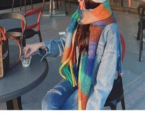 Detail of soft multi-color plaid scarf featuring vibrant green, orange, and blue knit patterns