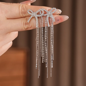 Macro view of silver bow-shaped tassel earrings with sparkling cubic zirconia stones