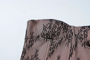 Détail de dentelle florale noire sur doublure rose nude d'un corset avec coutures