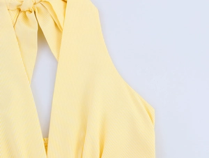Détail de la robe licou à rayures jaunes montrant la texture coton et le nœud papillon