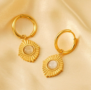 Détail de boucles d'oreilles vintage dorées avec pierre œil de chat sur fond en soie