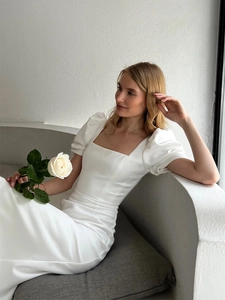 Close-up of elegant square neckline and puff sleeves on white satin dress with pleats