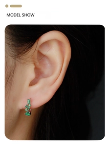 Close-up of S925 silver hoop earrings with emerald green gemstones worn by a model