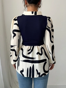 Detail of a casual printed blouse featuring contrast knit back panel and puff sleeves