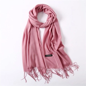 Detail showing soft pink cashmere scarf texture with delicate fringe and label