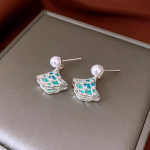 Macro shot of silver fan-shaped ginkgo leaf earrings with blue enamel and pearl details