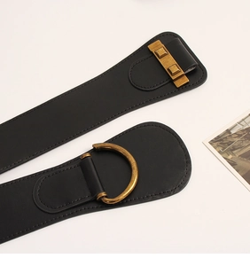 Detail of vintage black wide waist belt featuring textured leather and antique gold D-ring