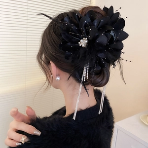 Détail d'une pince à cheveux fleur noire avec plumes et longs pompons en strass