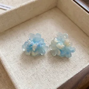Elegant 3D blue and white gradient flower stud earrings presented in a wooden jewelry box