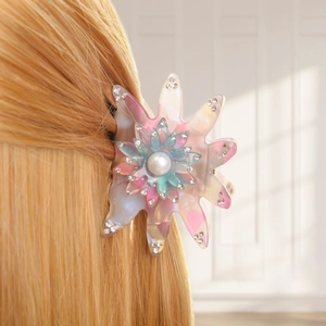 Détail d'une pince à cheveux en forme de fleur en résine avec perles et strass