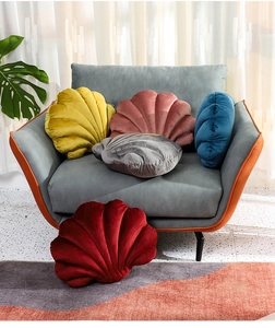 Plush velvet shell pillows in various colors displayed on a stylish gray armchair