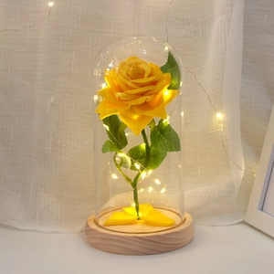 Preserved yellow rose in glass dome with LED string lights on round wooden base