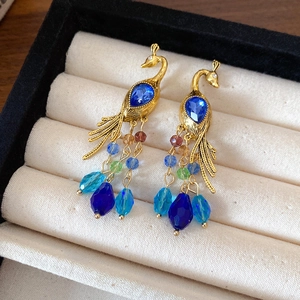 Vue détaillée de boucles d'oreilles paon vintage avec gemmes bleues et perles