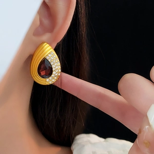 Close-up of vintage teardrop earrings with red gemstone and diamonds on model