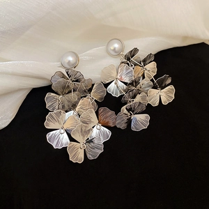 Detailed macro view of silver hollow layered flower earrings with pearl studs and tassels
