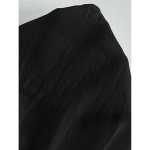 Close-up of black breathable linen-like fabric showing the fine woven texture of the shorts