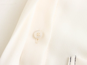 Detailed macro view of the cream blouse showing fabric texture and translucent buttons