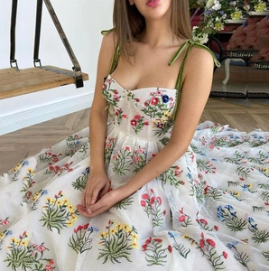 Detail der Stickerei auf weißem Netzkleid mit Samträgern und floralem Muster