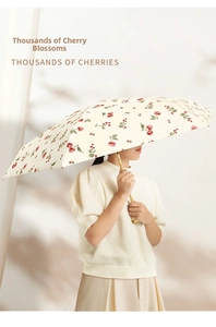 Detail of vintage cherry print parasol with cream fabric and gold metal handle