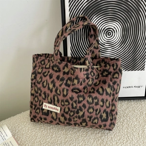 Close-up of leopard print plush handbag with pink and brown texture and brand label