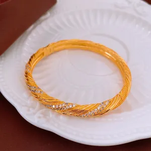 Vintage gold plated twisted bangle with zircon accents on a white decorative plate