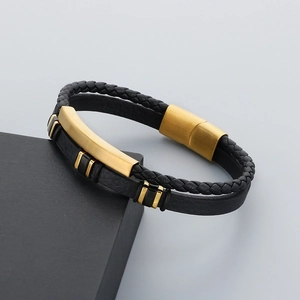 Macro detail of black braided leather strap and matte gold curved metal bar on a bracelet