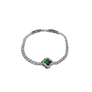 Elegant silver tennis bracelet with a green clover pendant and pavé zircons on white backdrop