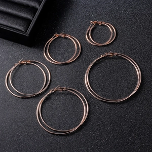 Flat lay of five different sized rose gold hoop earrings on a black textured background