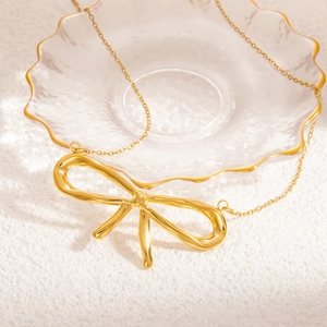 Elegant 18K gold plated stainless steel bow necklace on a textured white background