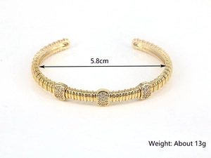 Detail of 5.8cm gold open bangle featuring threaded tube design and zircon accents