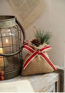 Detail showing linen Christmas gift bag with pine cones, red berries and a striped bow