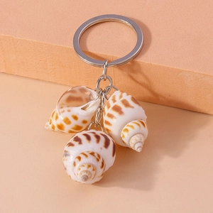 Natural conch shell keychain with silver metal ring on a minimalist beige background