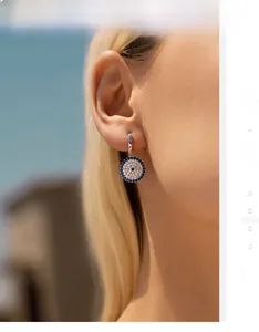Detail of S925 sterling silver evil eye earrings with blue and white crystals on ear