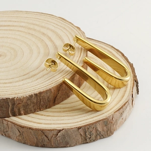 Boucles d'oreilles en forme de U en acier inoxydable doré sur blocs de bois