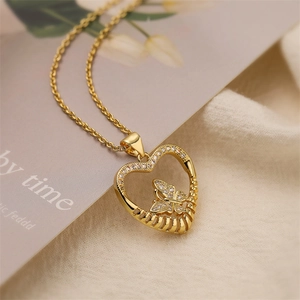 Detailed close-up of gold heart pendant with zircon butterfly on textured fabric