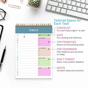 Flat lay of daily spiral planner with sections for priorities, checklist and notes on a desk